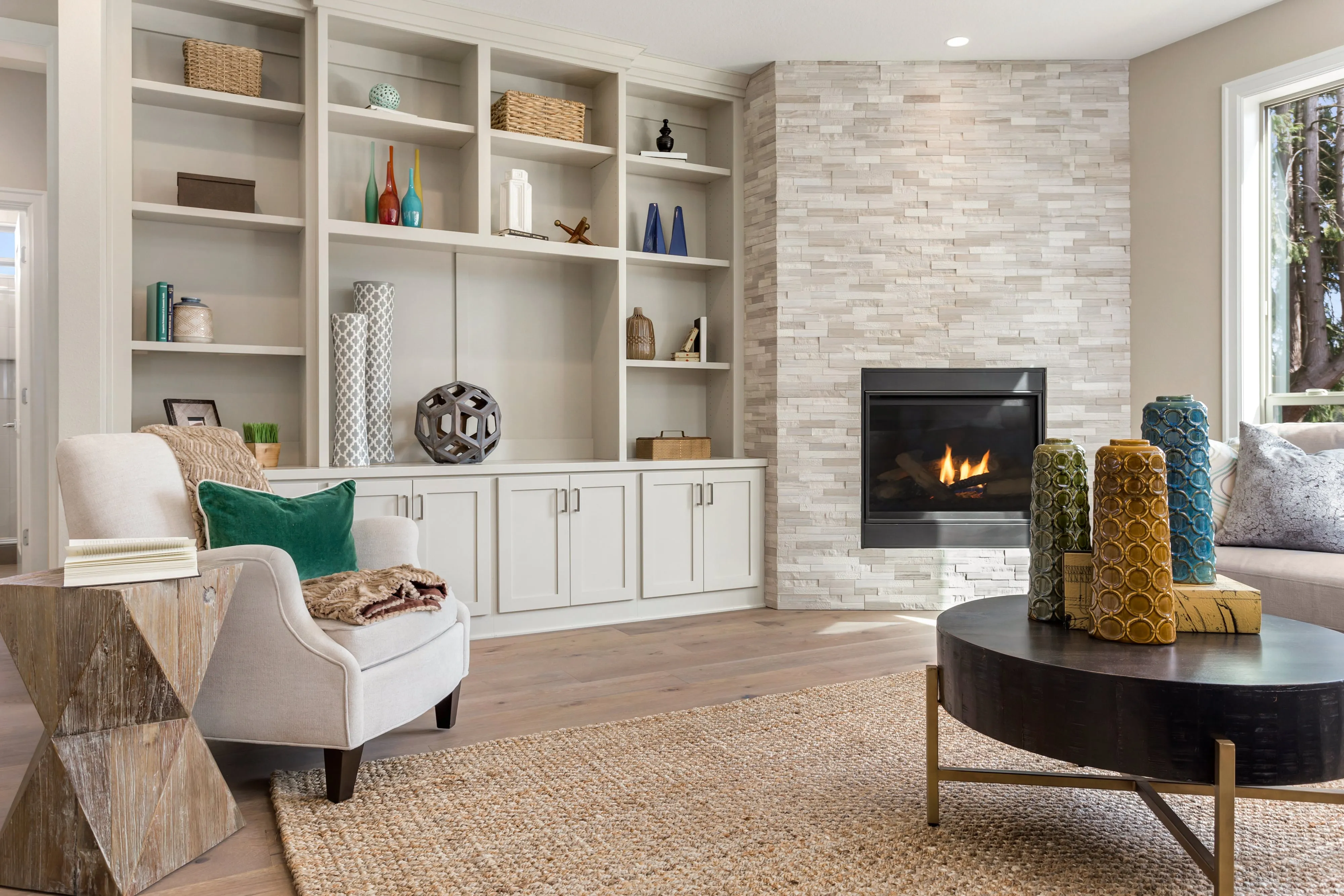 a living room with a arm chair, a coffee table, a book shelf and a fireplace