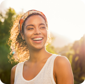 Beautiful african american woman smiling and looking away at park during sunset