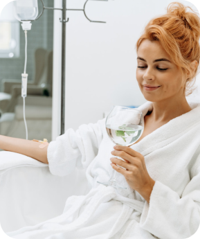 Woman in white bathrobe sitting in armchair and receiving IV infusion