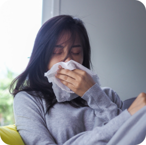 Sick girl sitting on the sofa in the house having a runny nose