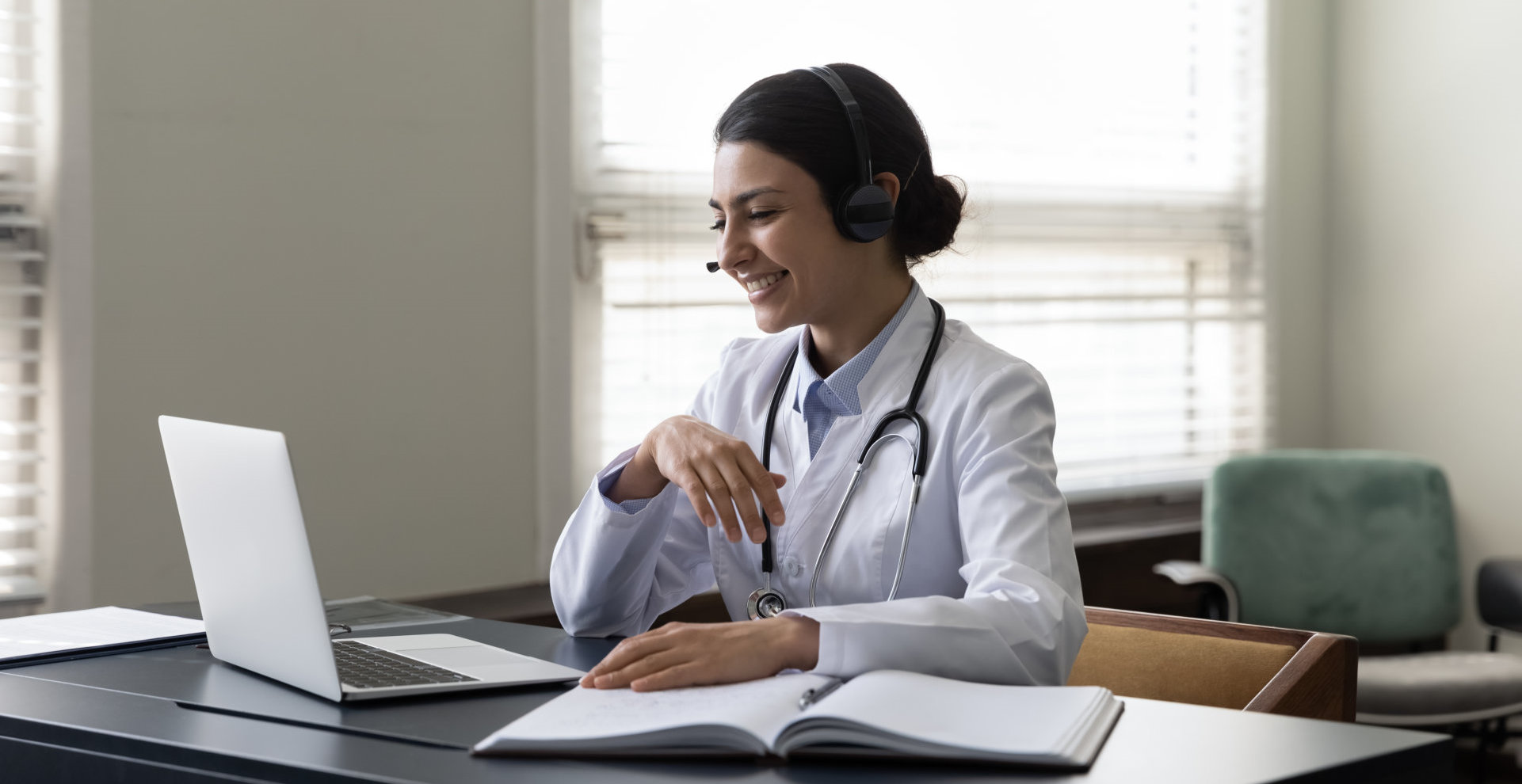 woman with stethoscope having a video call with someone on her laptop