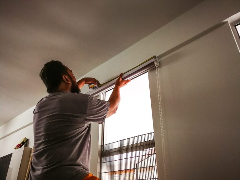 man-measure-and-install-curtain-panel-at-the-window-do-it-yourself-diy-man-at-work--e1638151803115